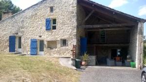 a large stone house with blue doors and windows at Ferme restaurée de vacance in Xaintrailles