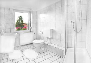a white bathroom with a toilet and a shower at Hotel Landhaus in Eschweiler