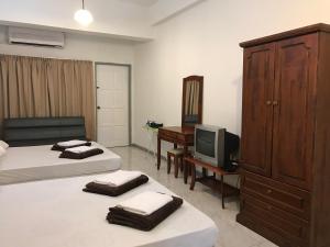1 Schlafzimmer mit 2 Betten, einem TV und einer Kommode in der Unterkunft Nusantara Mattwaddien M.S in Kota Kinabalu