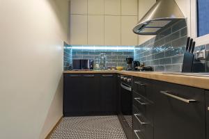 una cocina con armarios negros y azulejos azules en Photographers House en Atenas