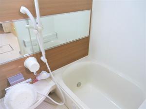 un bagno con una vasca bianca e un lavandino di Minpaku Mon a Sapporo