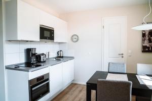 uma cozinha com armários brancos e uma mesa de jantar em Apartmentanlage Seezeichen em Ahrenshoop