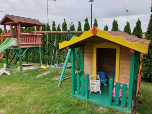 a playground with a play house and a slide at Domki letniskowe Sawinda in Rewal