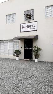 a white building with a hotel sign and two potted plants at Hotel Bella Júlia in Joinville