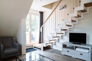 a living room with a staircase and a television at Apartmentanlage Seezeichen in Ahrenshoop