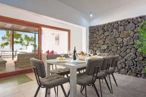 a dining room with a table and chairs and a stone wall at Villa Corito in Playa Blanca