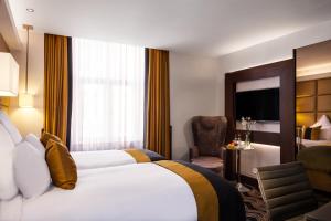 a hotel room with two beds and a television at The Piccadilly London West End in London