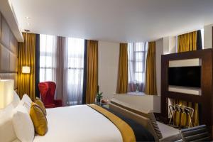 a hotel room with a bed and a flat screen tv at The Piccadilly London West End in London