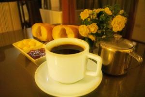 a cup of coffee on a plate with bread and flowers at Hostal Siglo 21 in Tacna