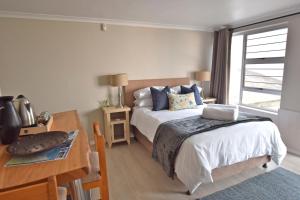 a bedroom with a bed and a table and a desk at Apartment Dolphin House in Hermanus