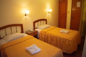 Dos camas en una habitación de hotel con toallas. en Hostal Siglo 21, en Tacna