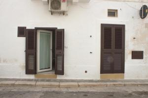 a white building with brown shutters and a window at Casa Nori in Polignano a Mare