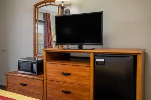 a television on top of a wooden dresser with a microwave at Days Inn by Wyndham Wilson in Wilson