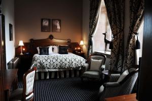 a bedroom with a bed and two chairs and a window at Peckforton Castle in Tarporley