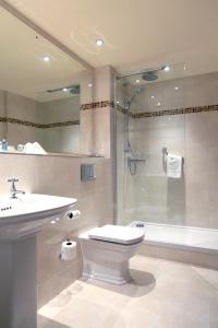 a bathroom with a toilet and a shower and a sink at Macdonald Craxton Wood Hotel & Spa in Ledsham