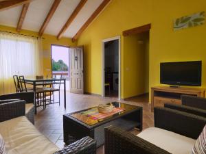 ein Wohnzimmer mit einem TV, Stühlen und einem Tisch in der Unterkunft Arriba y Abajo Cadiz in Zahora