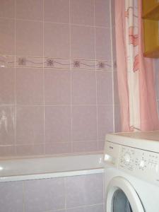 uma máquina de lavar roupa numa casa de banho em azulejos cor-de-rosa em Comfortable apartments in centre with 3 bedrooms em Rivne