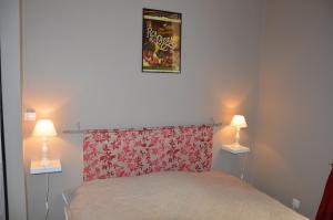 a bedroom with a bed with a red headboard and two lamps at Logis du Cagaïre in Le Puy en Velay