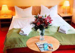 einen Tisch mit einer Blumenvase auf einem Bett in der Unterkunft Traditionsgasthaus Goldener Löwe Riesa in Riesa