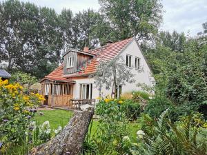 a white house with an orange roof in a garden at Fachwerkhaus am Fluss in Neuhardenberg