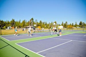 a group of people playing tennis on a tennis court at Bend-Sunriver Camping Resort Two-Bedroom Cabin 7 in Sunriver