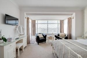 a bedroom with a bed and a desk and chairs at The Coast Yard B & B and Garden Chalets in Chichester