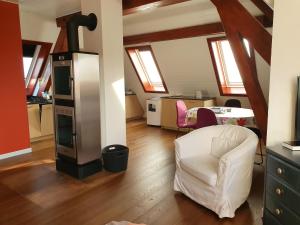 a living room with a white chair and a kitchen at Appartement Entre Monts et Lac court et moyen séjour in Nyon