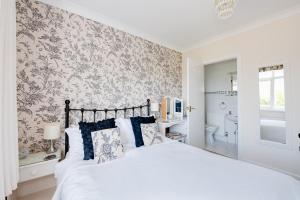 a bedroom with a white bed and a bathroom at The Coast Yard B & B and Garden Chalets in Chichester