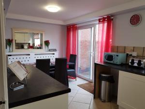 een keuken met rode gordijnen en een tafel met stoelen bij Penllech House - Huku Kwetu Notts - 3 Bedroom Spacious Lovely and Cosy with a Free Parking- Affordable and Suitable to Group Business Travellers in Nottingham