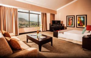 a hotel room with a bed and a couch and a table at Avani Lesotho Hotel & Casino in Maseru