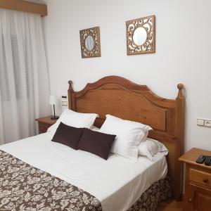 1 dormitorio con 1 cama grande con sábanas y almohadas blancas en Hostal La Parada, en Pedro Muñoz