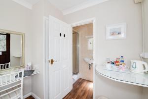 a white bathroom with a sink and a mirror at The Coast Yard B & B and Garden Chalets in Chichester