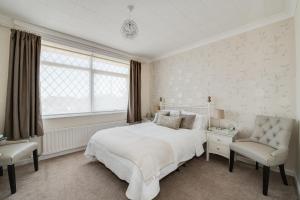 a white bedroom with a bed and a chair at The Coast Yard B & B and Garden Chalets in Chichester