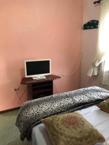 a bedroom with a bed and a computer monitor on a desk at Castelo Veraneio in Guarujá