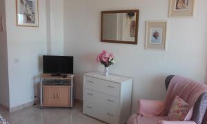 a living room with a tv and a dresser with a vase of flowers at Studio in Hercules with pool and sea view in Benalmádena