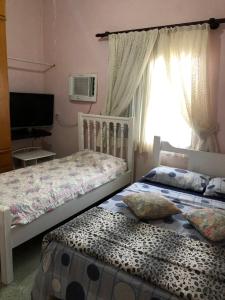 a bedroom with two beds and a television and a window at Castelo Veraneio in Guarujá