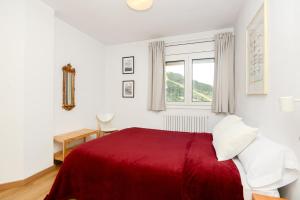 a white bedroom with a red bed and a window at Apartamento Fontargent in Soldeu
