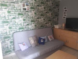 a couch against a brick wall with pillows on it at Maison Tifaloc in Montélimar