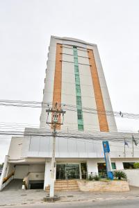 un edificio blanco alto con un reloj delante en Comfort Hotel Campos dos Goytacazes, en Campos dos Goytacazes