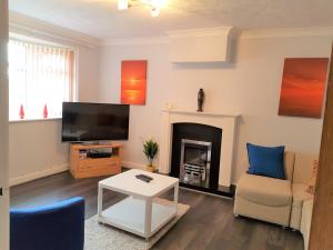 Penllech House - Huku Kwetu Notts - 3 Bedroom Spacious Lovely and Cosy with a Free Parking- Affordable and Suitable to Group Business Travellers في نوتينغهام: غرفة معيشة مع موقد وتلفزيون