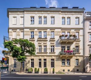Gem Apartment by Castle (Old Town Krakow) في كراكوف: مبنى ابيض كبير عليه علب ورد