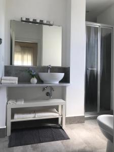 a white bathroom with a sink and a mirror at La Finestra Sull'Etna in Motta SantʼAnastasia