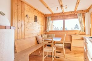 una cucina con pareti in legno, tavolo e sedie di Tielerhof ad Aldino