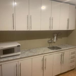 a kitchen with white cabinets and a sink and a microwave at Terrace Furnished Apartments- Hawally 1 in Kuwait