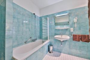 baño de azulejos azules con bañera y lavamanos en Hôtel Bar Des Vosges, en Munster