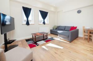 a living room with a couch and a flat screen tv at easyStay Slough Central Apartment in Slough