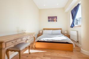 a bedroom with a bed and a desk and a window at easyStay Slough Central Apartment in Slough