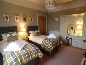 Thornsgill House Bed & Breakfast في آسكريج: غرفة نوم بسريرين ومكتب مع مرآة