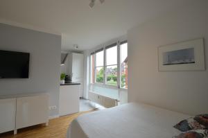 a white bedroom with a bed and a flat screen tv at Fair Apartment MAX 33 in Meerbusch