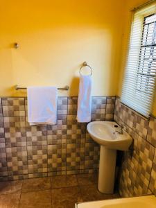 a bathroom with a sink and a toilet and towels at Maite Villa Lodge in Thohoyandou